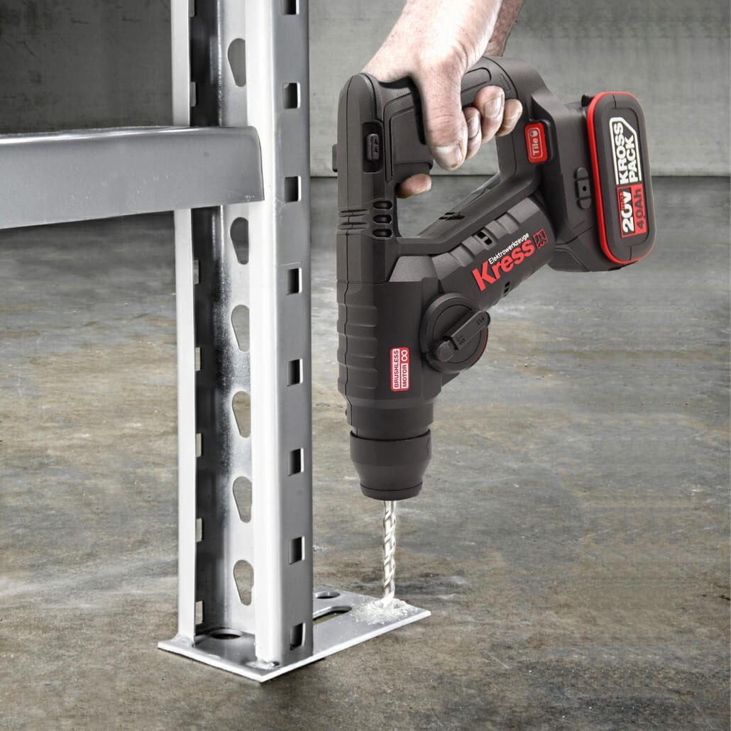 Bir adam Kress matkapla metal raf braketini deliyor.