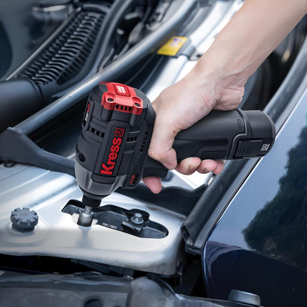 El, bir arabanın motor bölmesinin yakınında siyah ve kırmızı Kress darbeli anahtar tutuyor.