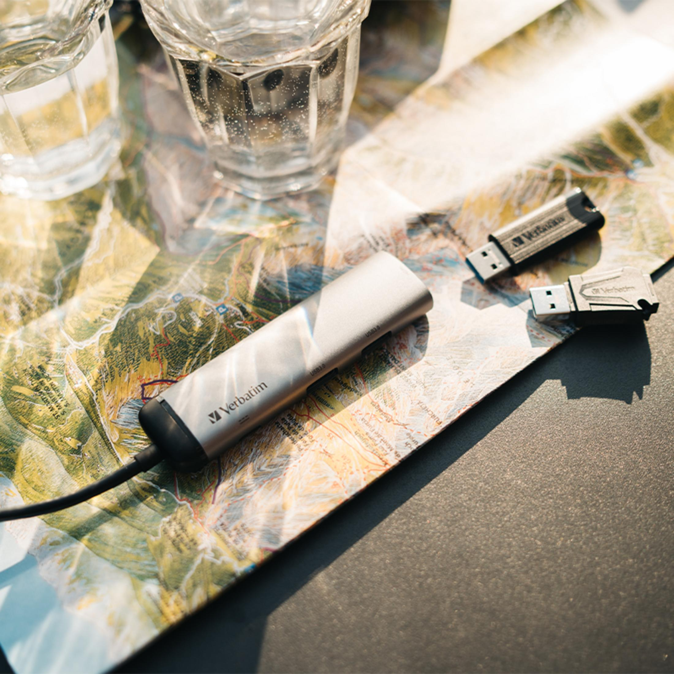 Zwei Gläser Wasser stehen auf einer Landkarte neben drei USB-Sticks.