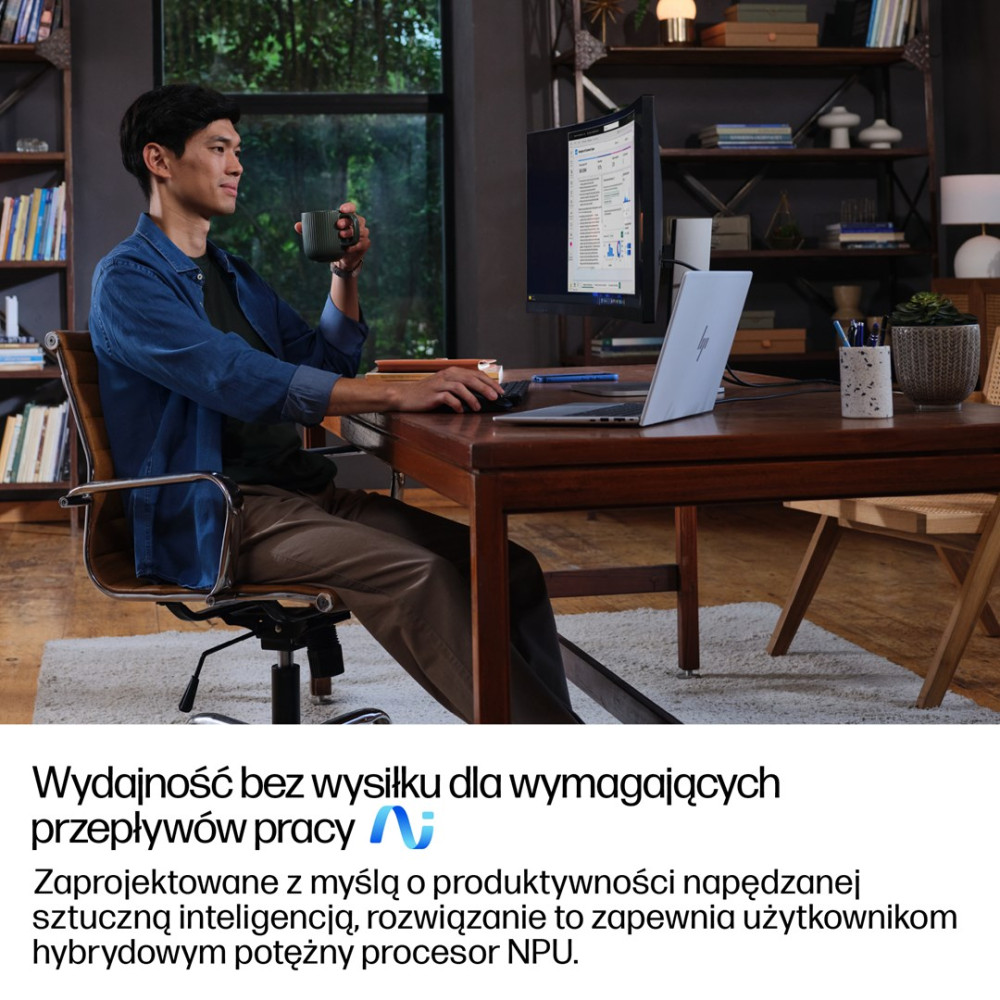 Mężczyzna siedzi przy biurku, pije kawę, pracuje na laptopie i monitorze.