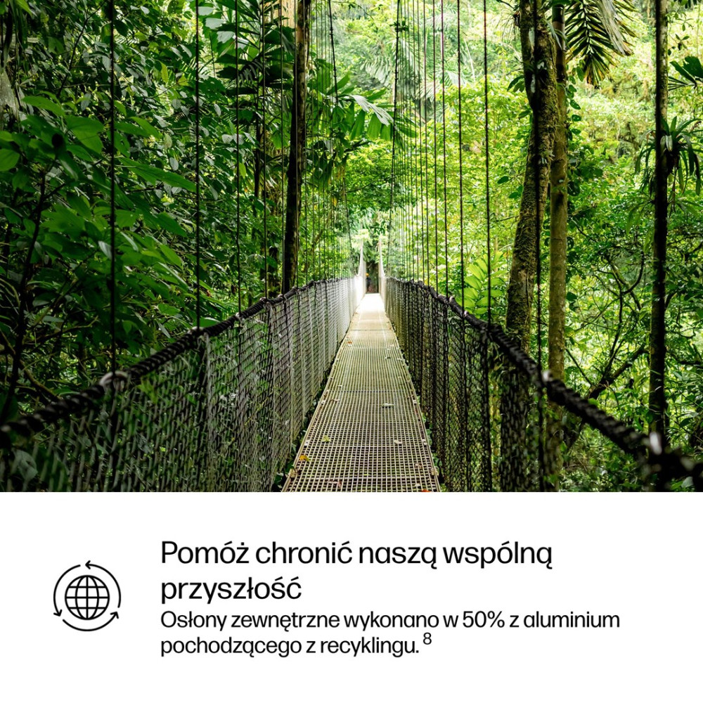 Most wiszący przecina bujną, zieloną dżunglę, z drzewami po obu stronach.
