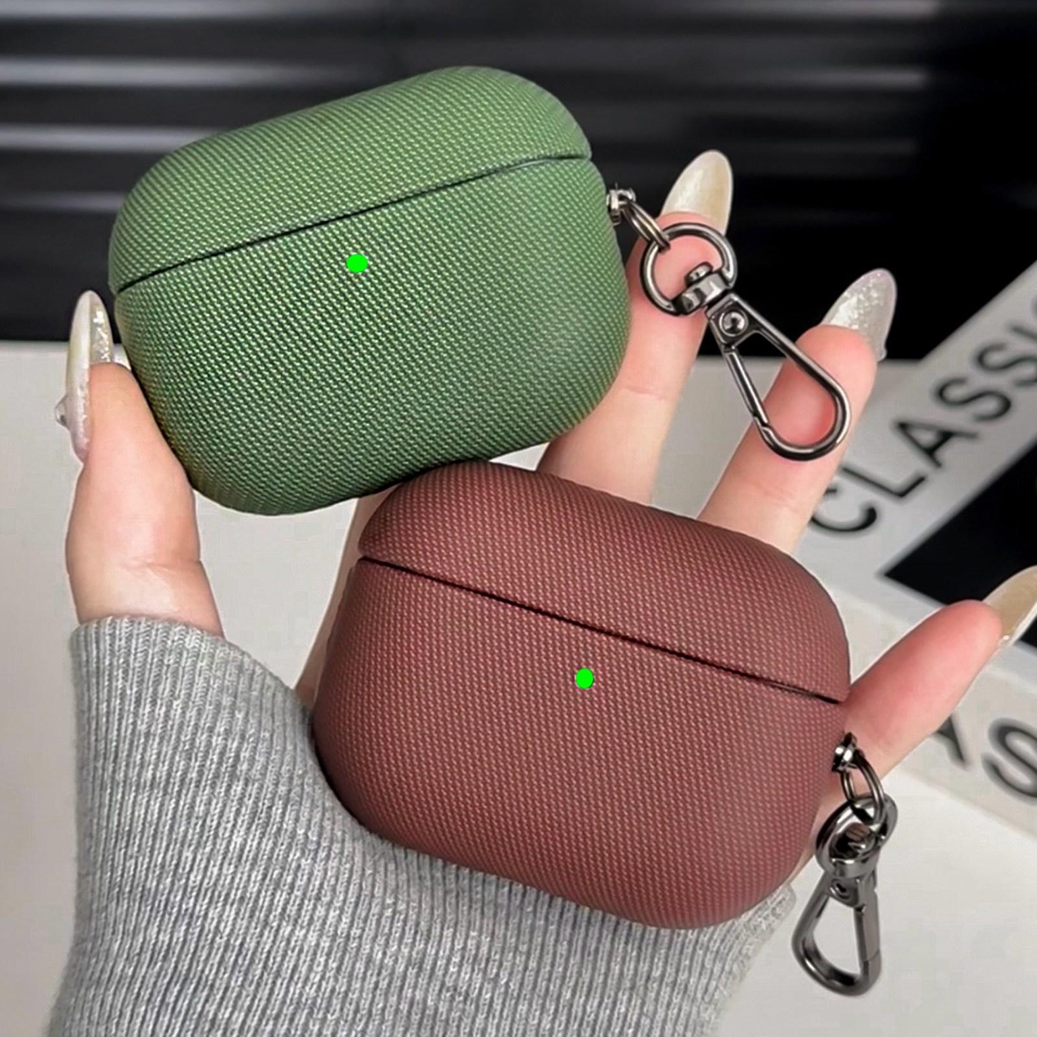 Dos fundas de auriculares, una verde y otra marrón, apiladas en una mano.