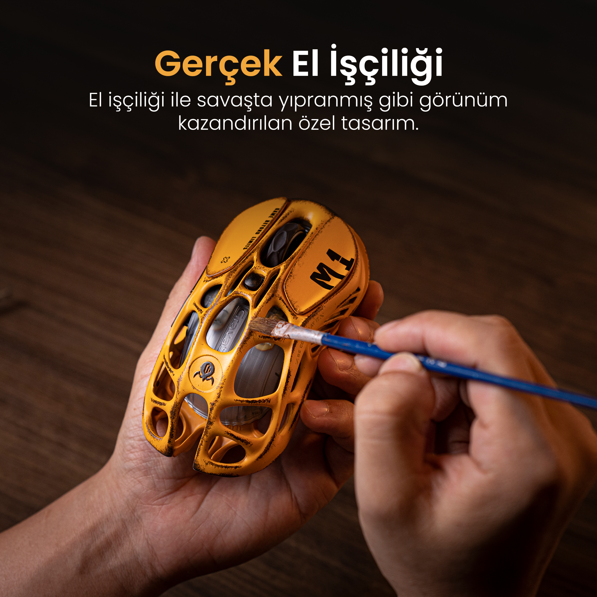Bir el, fırçayla sarı, yıpranmış görünümlü bir fareyi boyuyor.