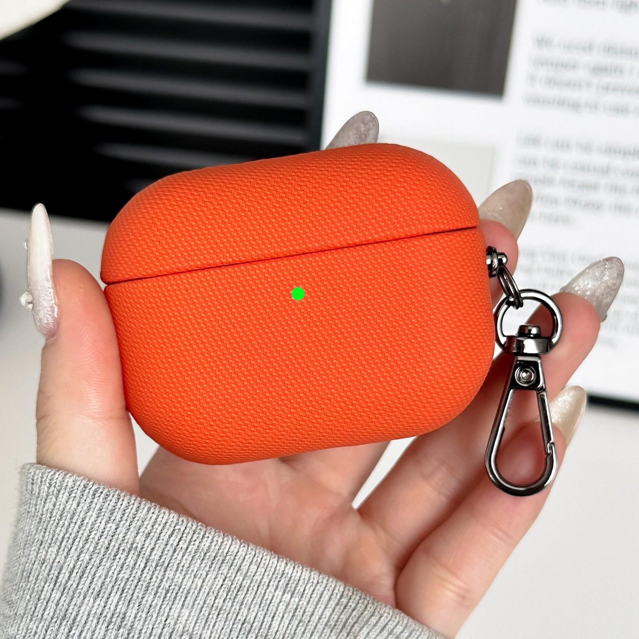 Una funda naranja para auriculares con un mosquetón en una mano.