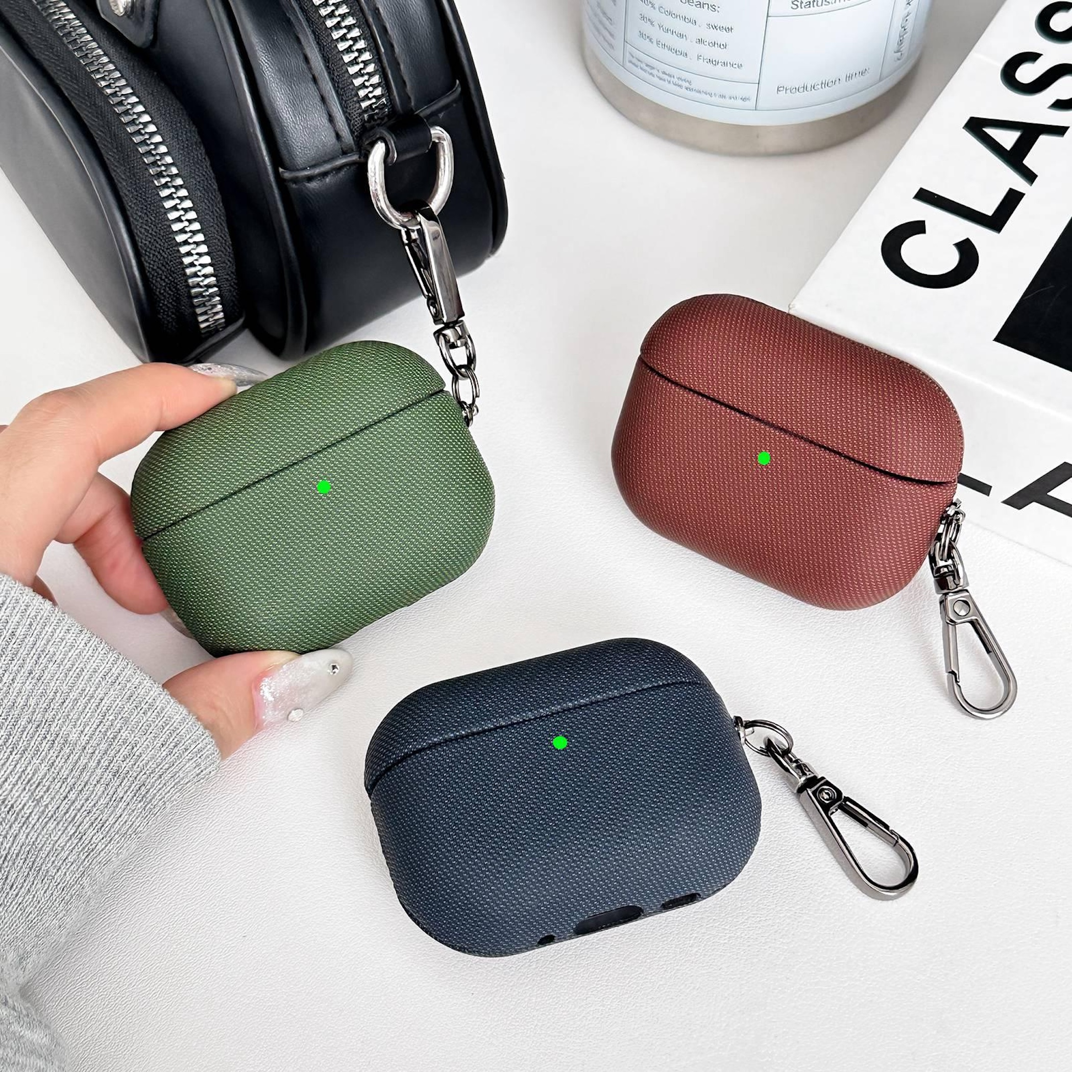 Tres fundas para auriculares: verde, rojizo y azul oscuro, con mosquetones.