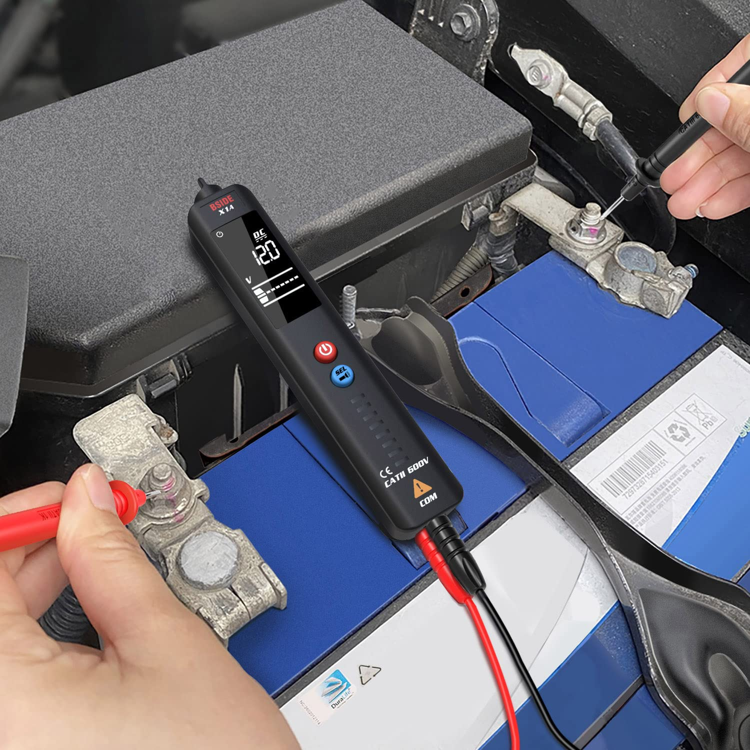 Ein Messgerät testet eine Autobatterie, die eine blaue Abdeckung hat.