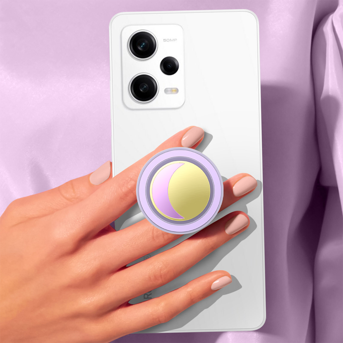 Una mano sostiene un teléfono blanco con un agarre de luna creciente morado y dorado.