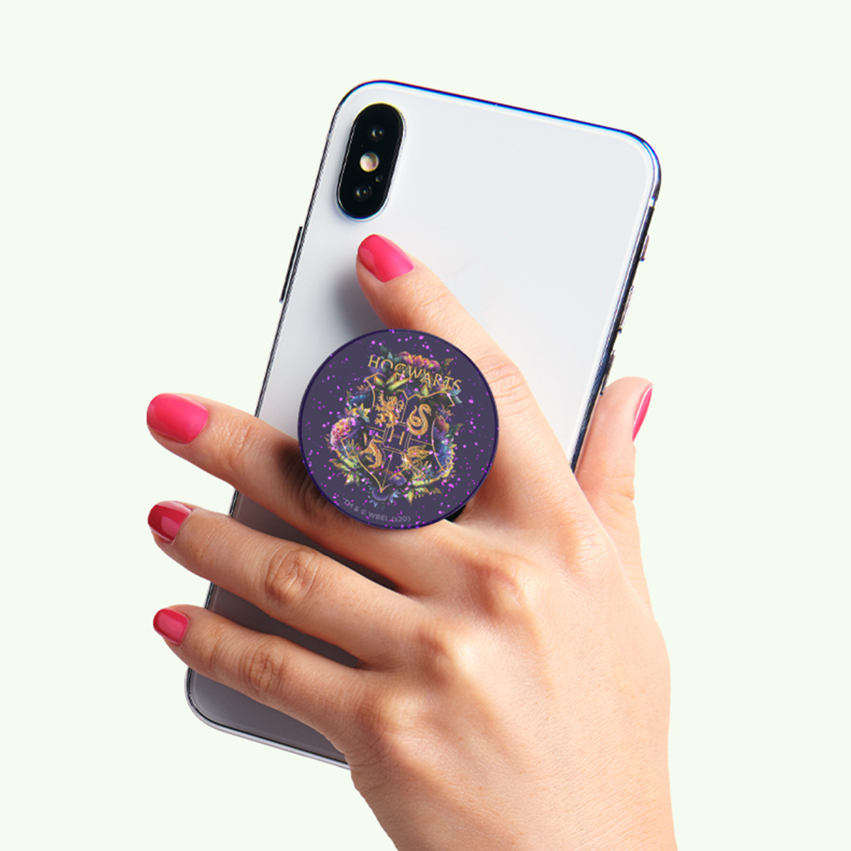 Una mano sostiene un smartphone con un adhesivo de Hogwarts.