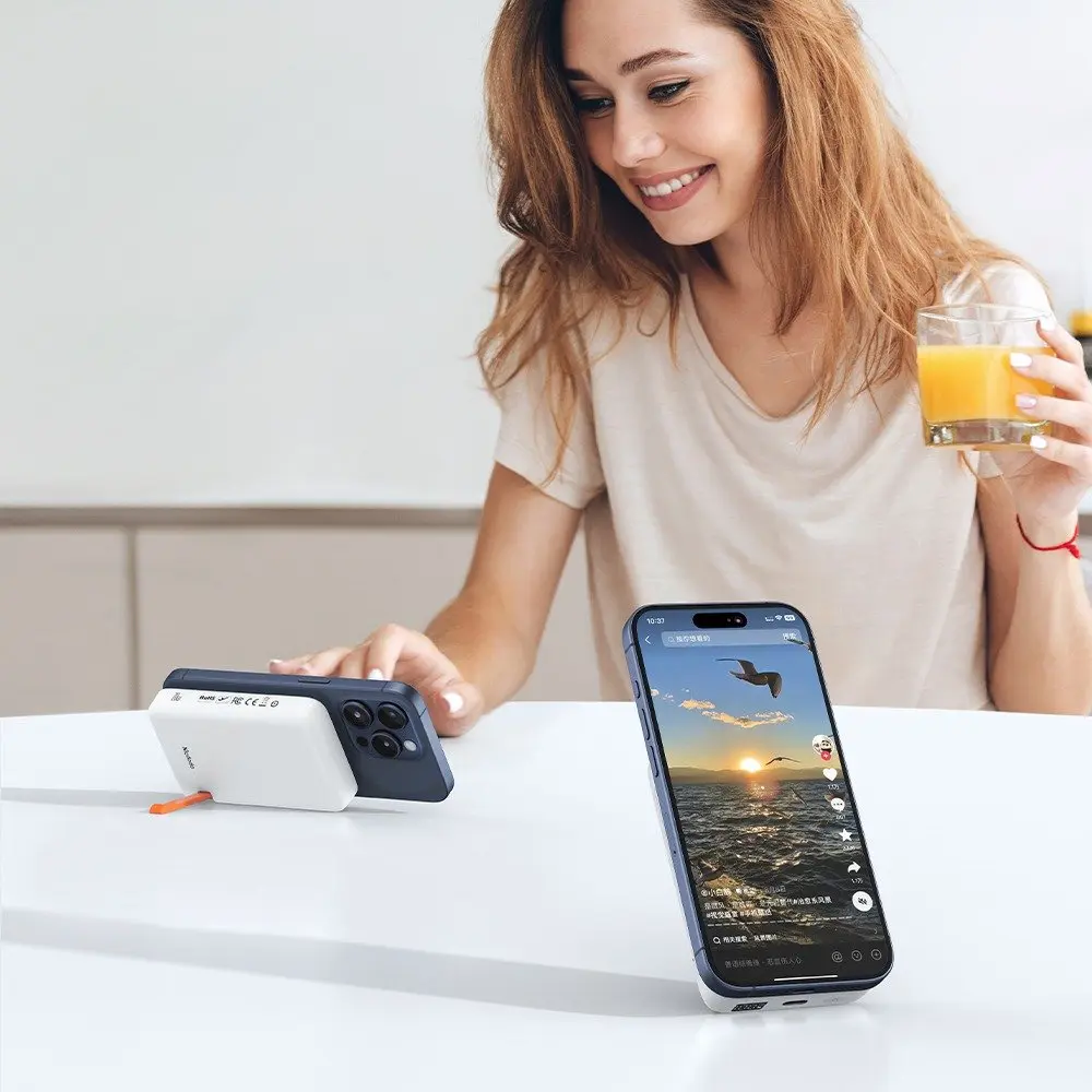 Kadın meyve suyu içiyor ve masadaki iki telefona bakıyor.