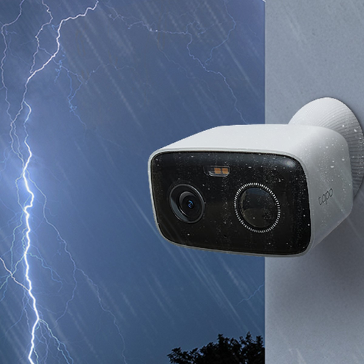 Una telecamera di sicurezza bianca su un muro, sotto pioggia e temporale.