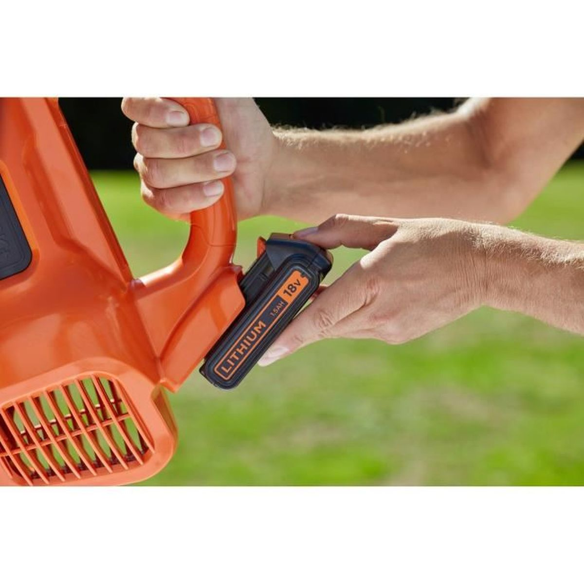 Una mano assembla un soffiatore per foglie arancione con batteria da 18V.