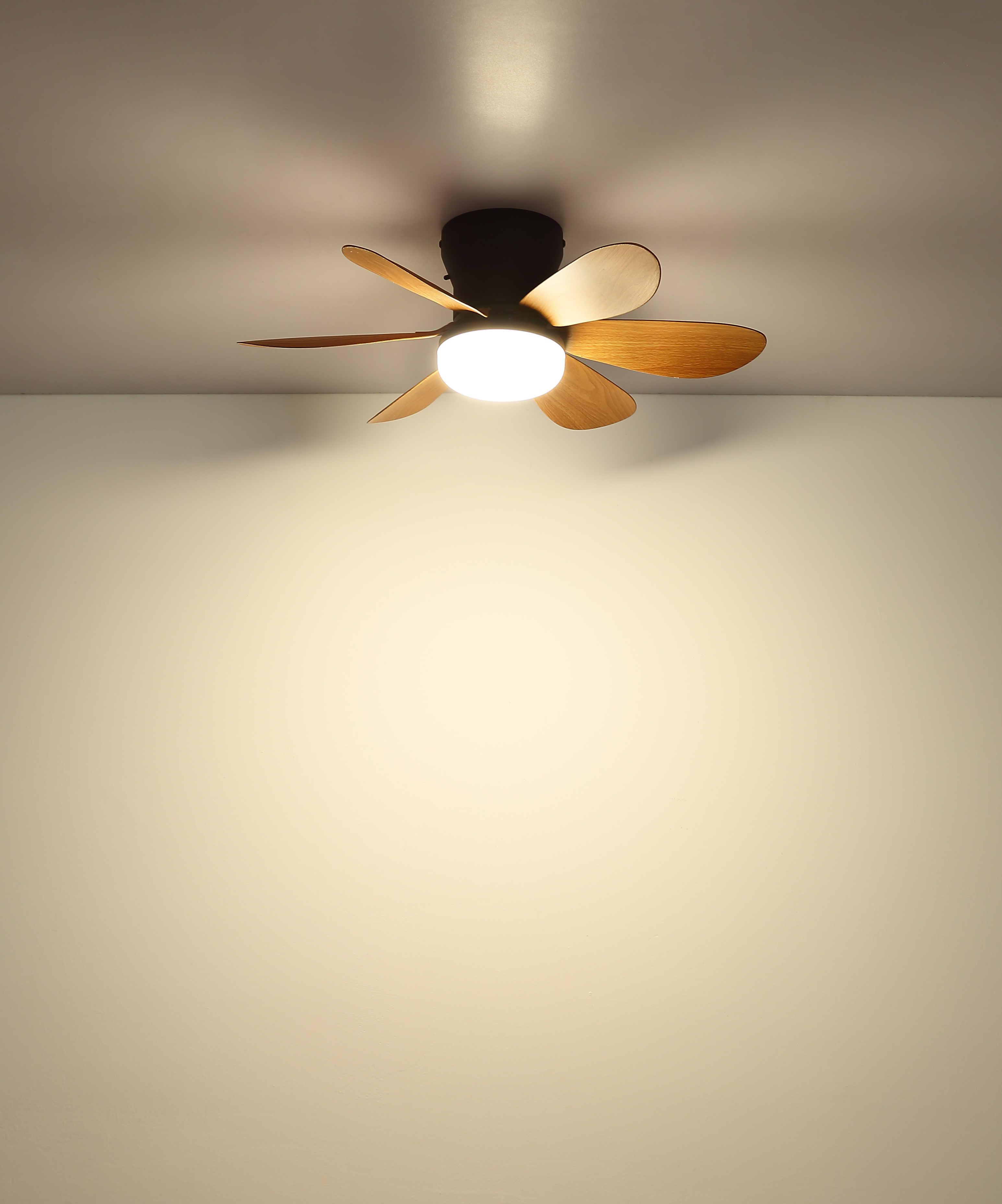 Ein Deckenventilator mit Holzflügeln und integrierter Lampe leuchtet von der Decke.