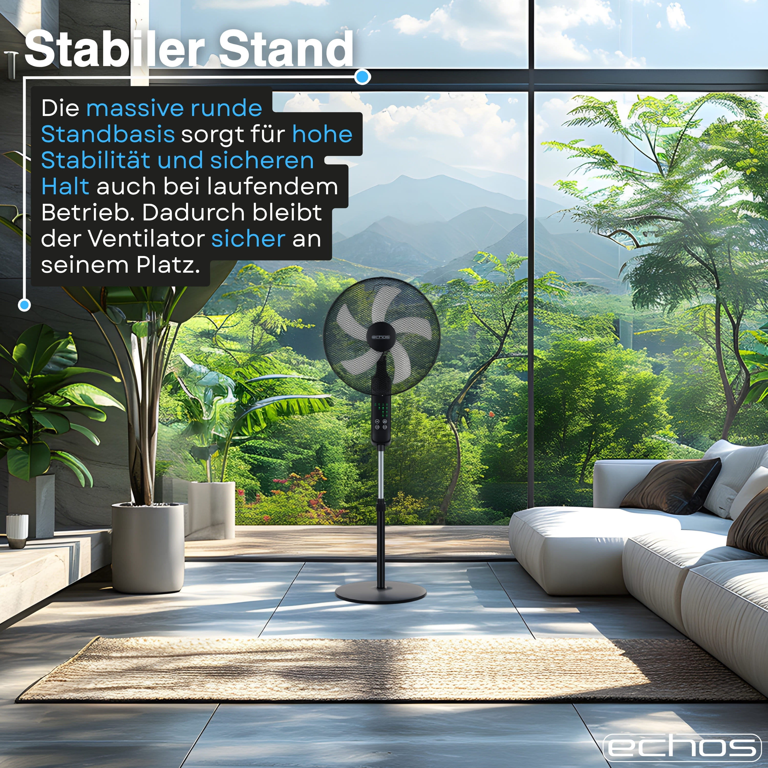 Ein schwarzer Ventilator steht vor einem Fenster mit Bergblick. Daneben ein Sofa.
