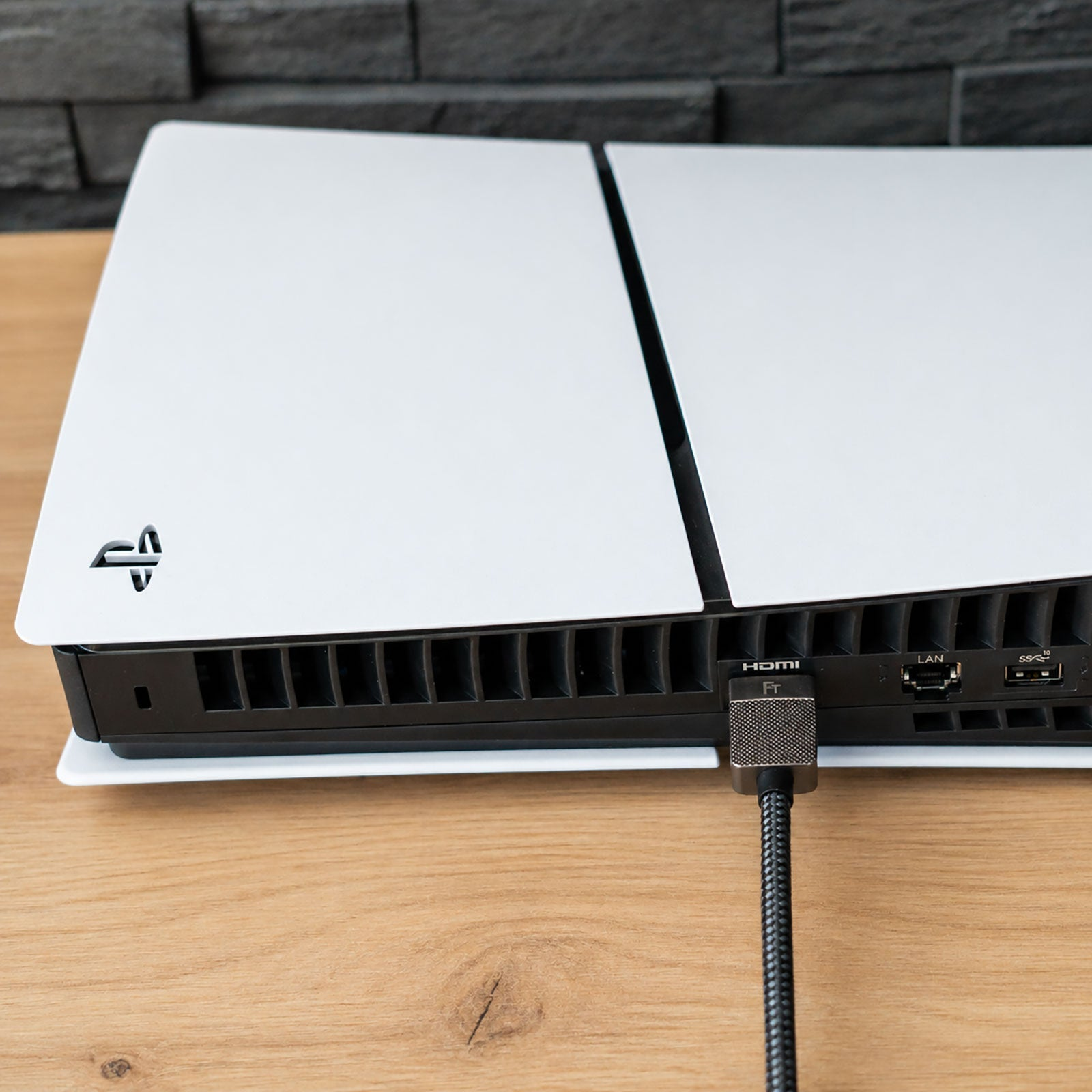Eine weiße Spielkonsole mit HDMI- und LAN-Anschlüssen, ein Kabel ist eingesteckt.