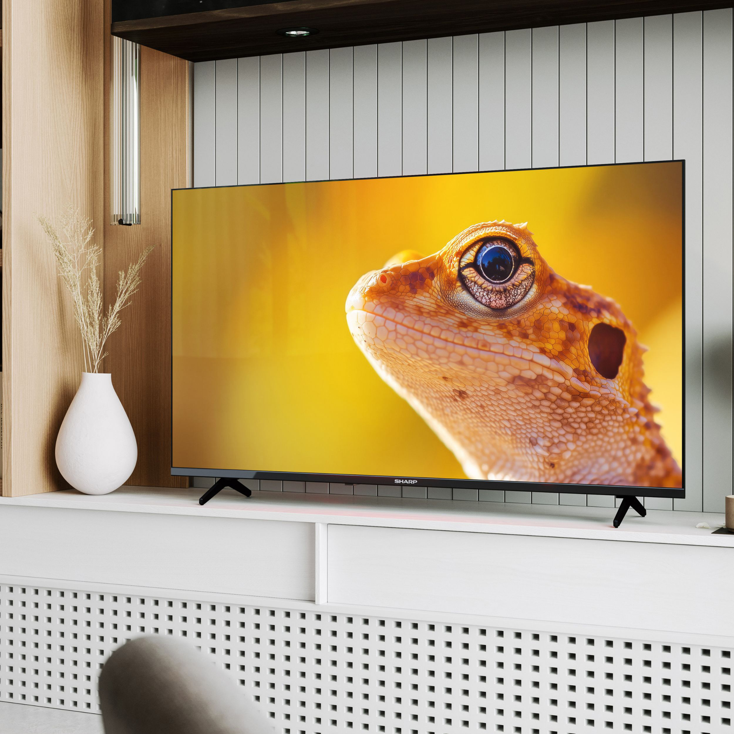 Nahaufnahme einer Eidechse auf einem Fernseher mit gelbem Hintergrund.