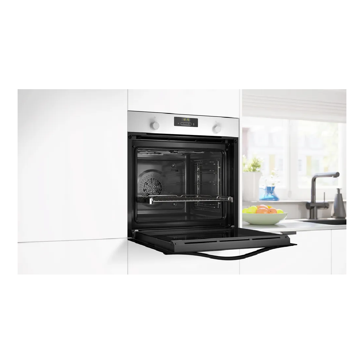 Un forno moderno con porta aperta, accanto a lavello e ciotola di frutta.