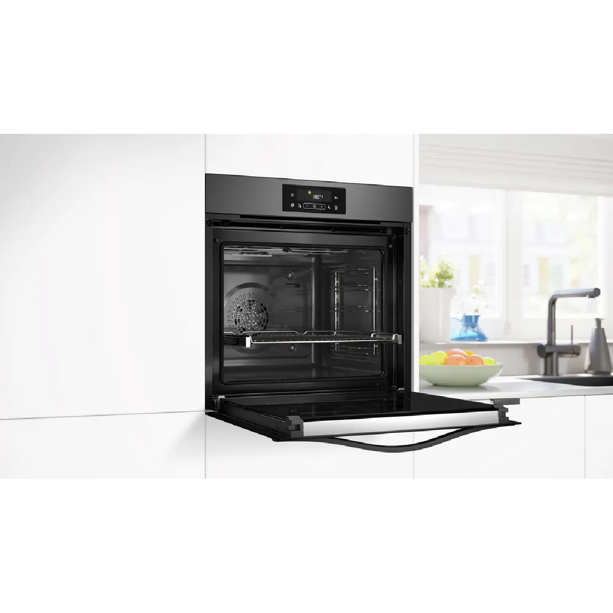 Un forno da incasso moderno con porta aperta in una cucina. Una ventola è visibile.