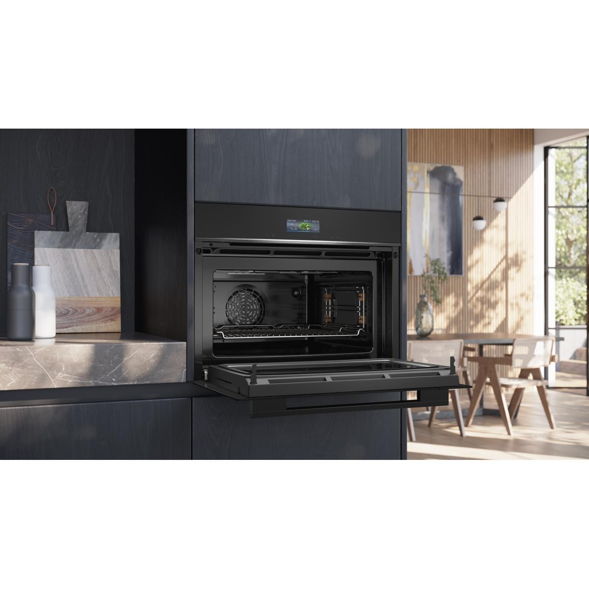 Forno da incasso moderno con porta aperta, accanto a tavolo e sedie.