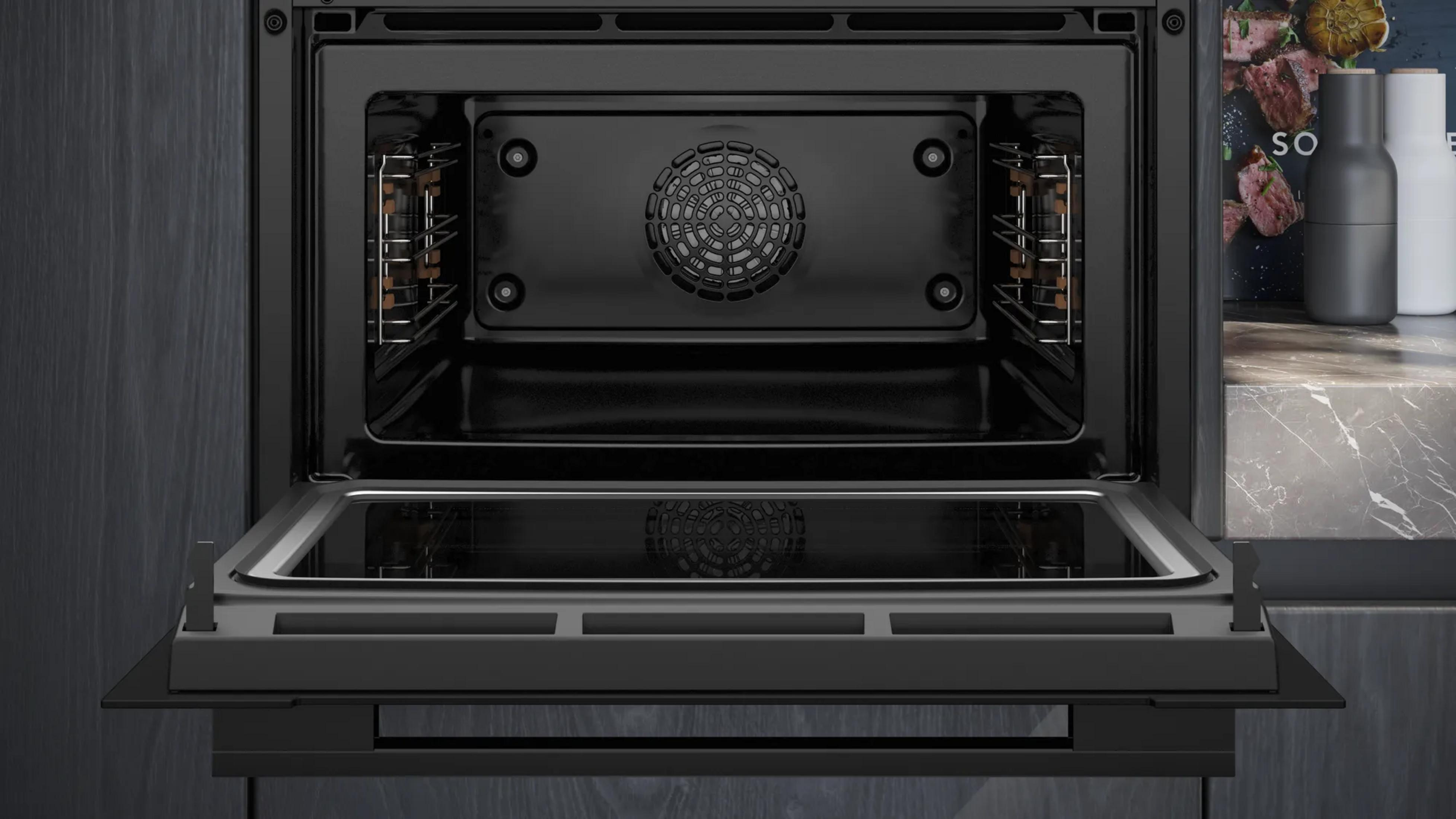 Un forno da incasso moderno e aperto con pannello scuro e ventola visibile.