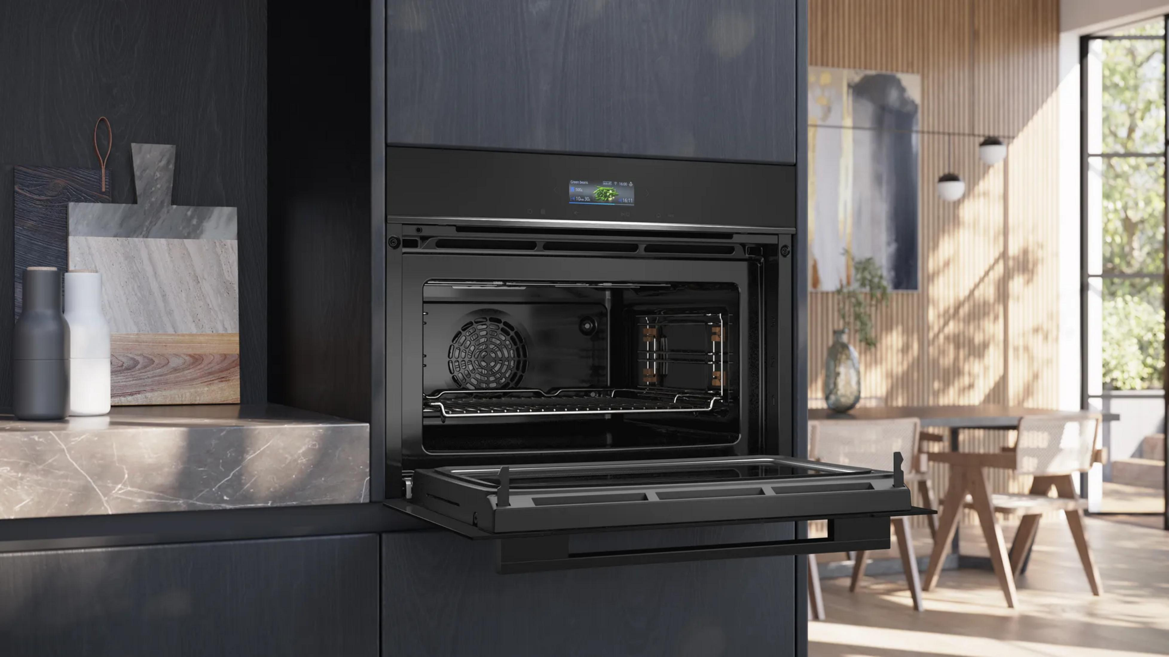 Un forno nero moderno con porta aperta e display. Accanto, piano di lavoro in marmo con bottiglie.