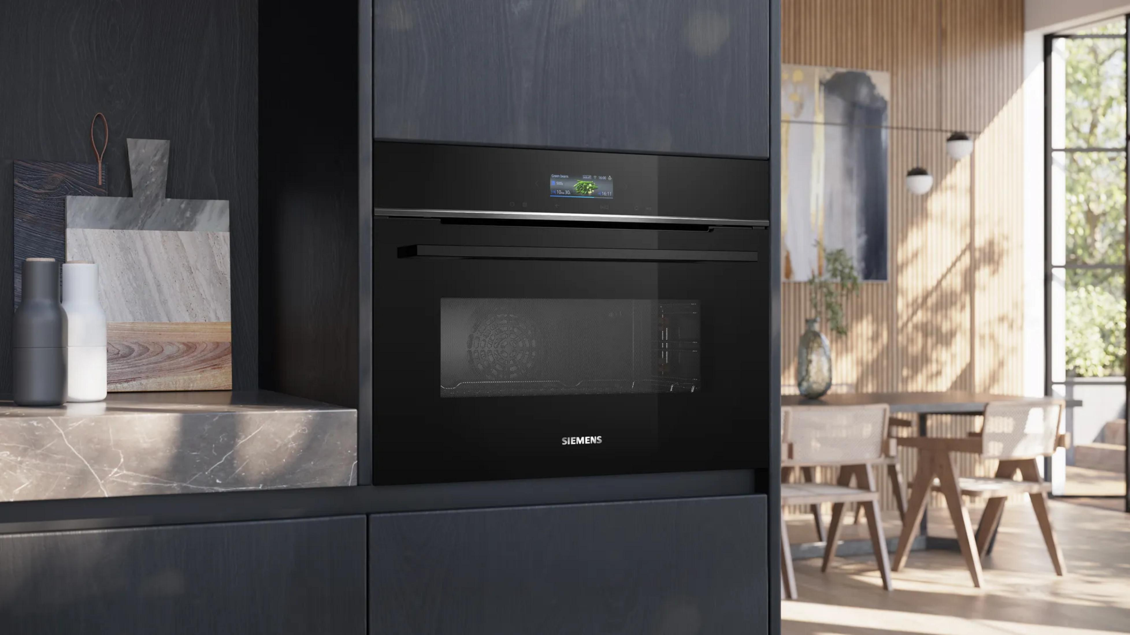 Forno da incasso nero moderno con touchscreen, tavolo da pranzo e sedie sullo sfondo.