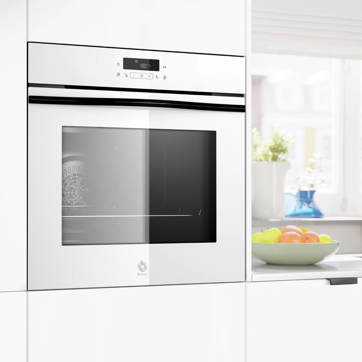 Forno da incasso bianco con display digitale impostato a 180 gradi. Una ciotola di frutta è visibile.