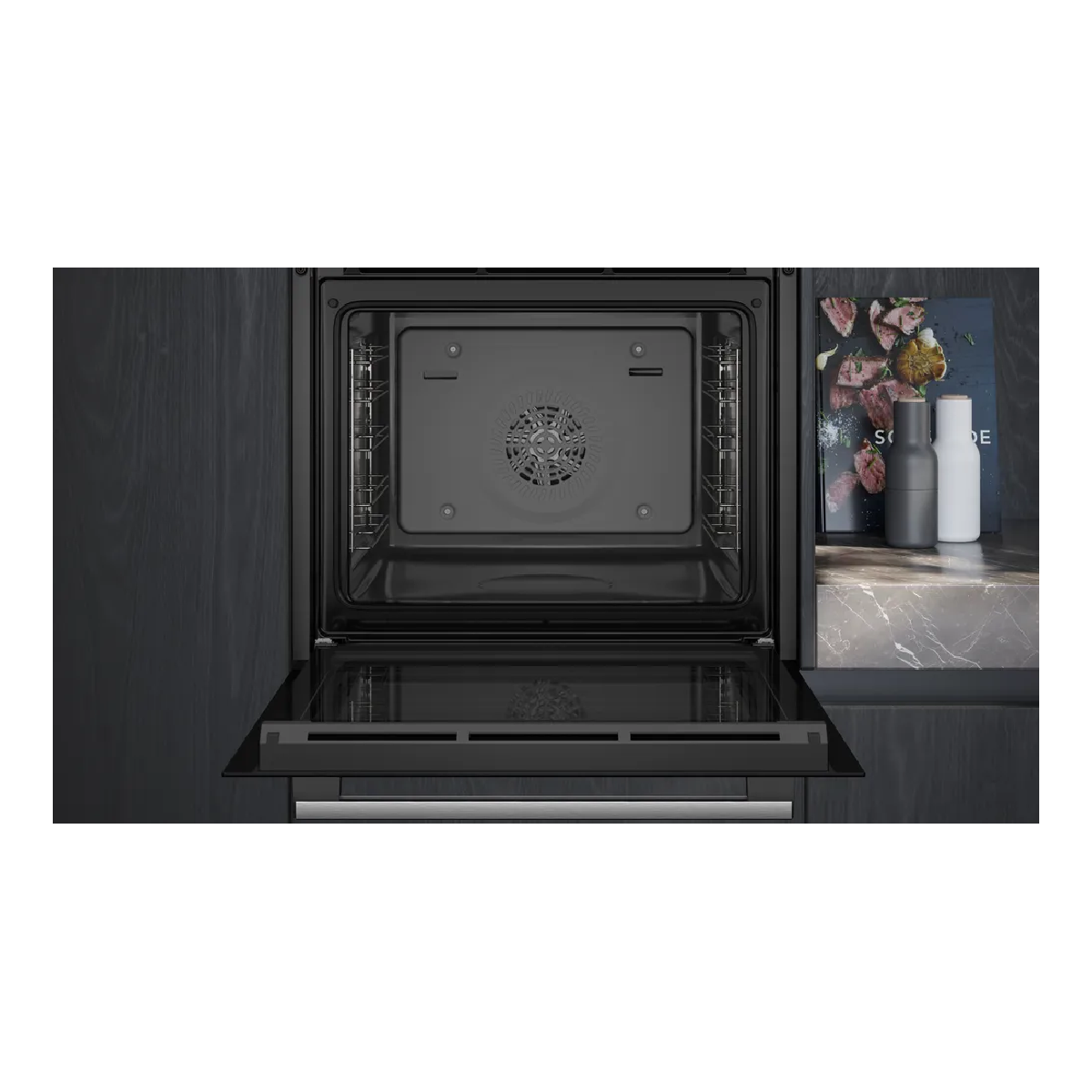 Un forno da incasso aperto con interno nero e grill. Macinini per spezie accanto.