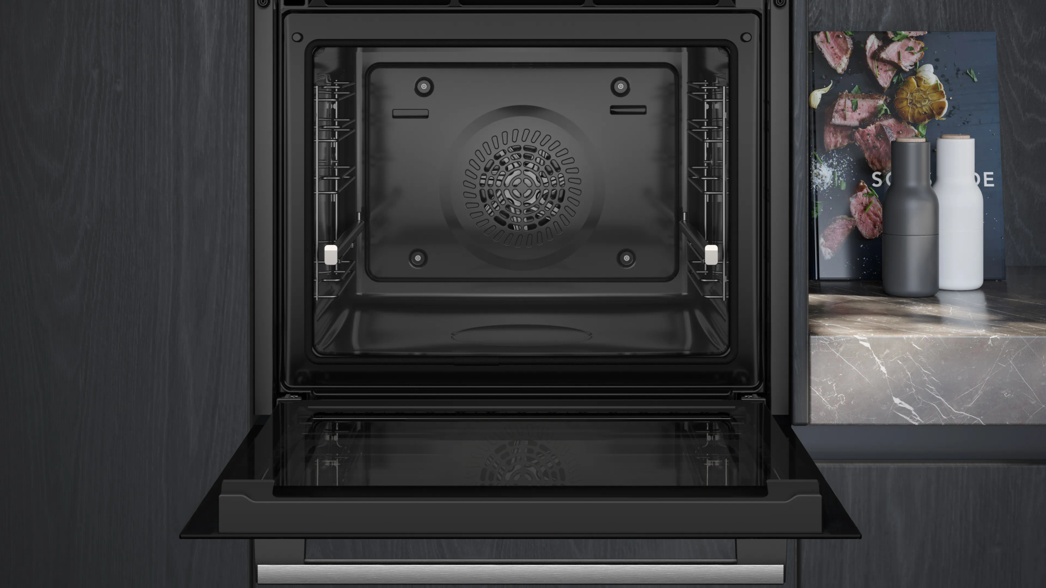 Un forno da incasso moderno e aperto con interno nero e griglia del ventilatore.