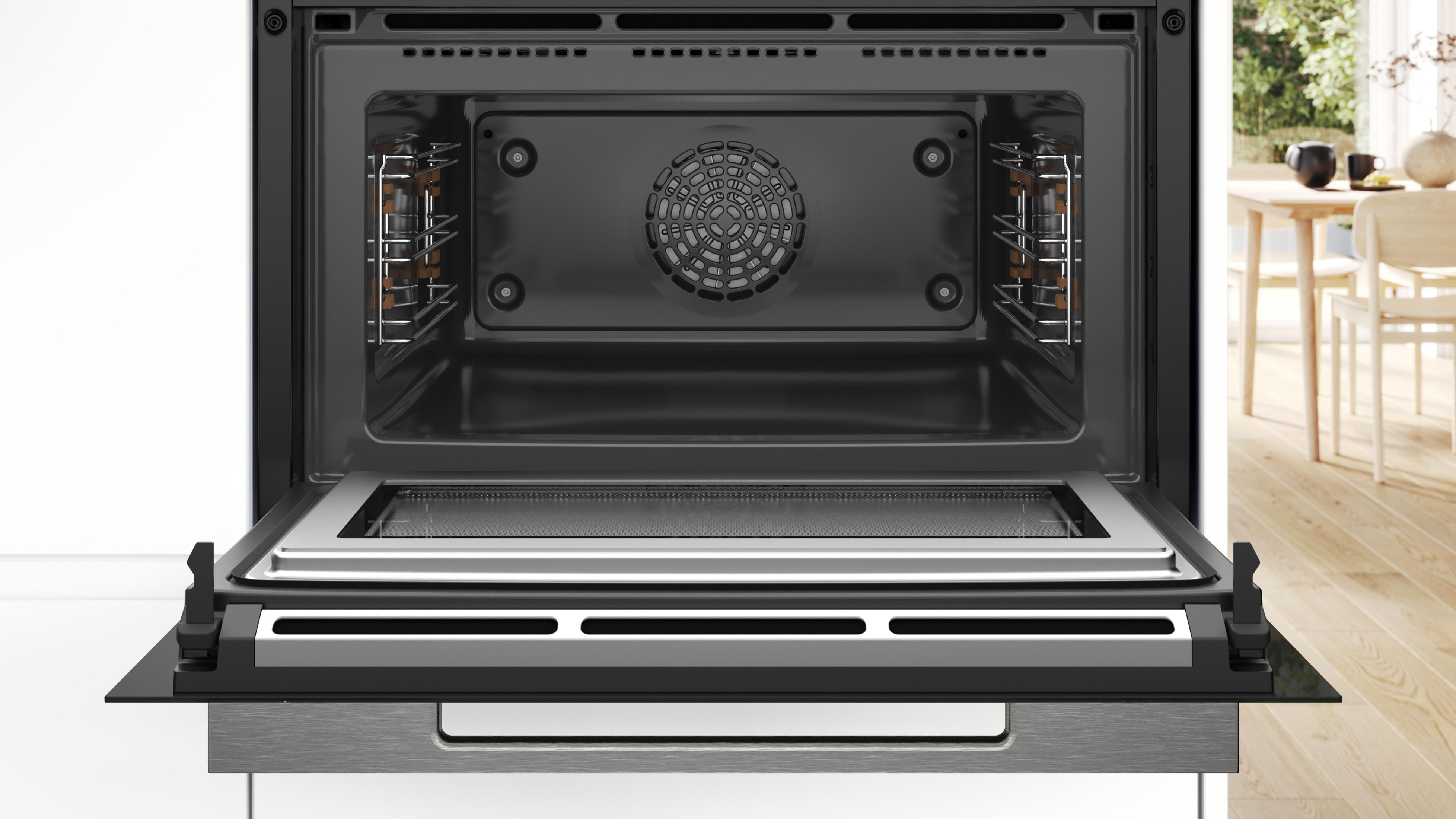 Un four encastrable ouvert avec des grilles argentées et une grille de ventilation.