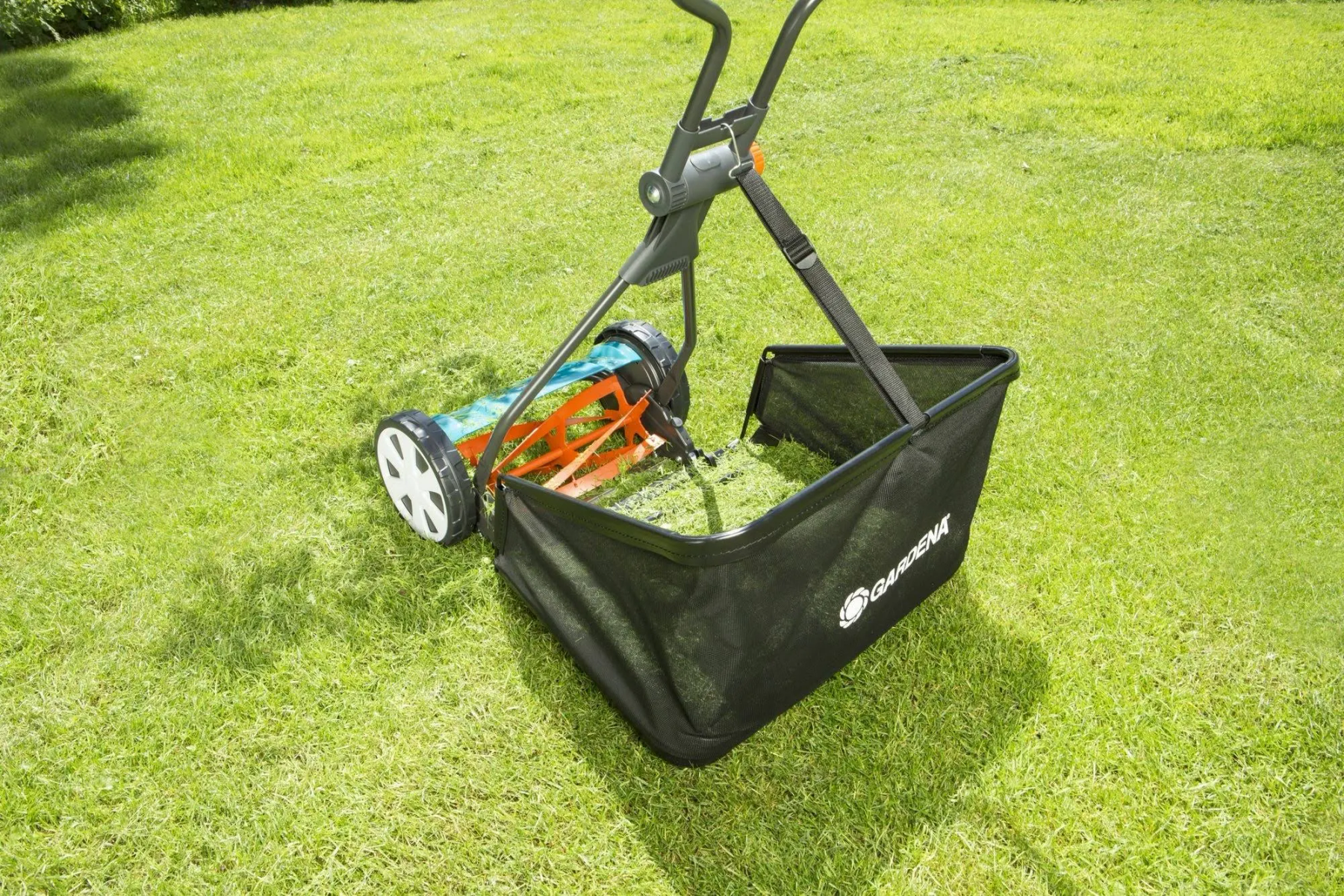 Un cortacésped de empuje Gardena con recogedor de césped sobre un césped verde.