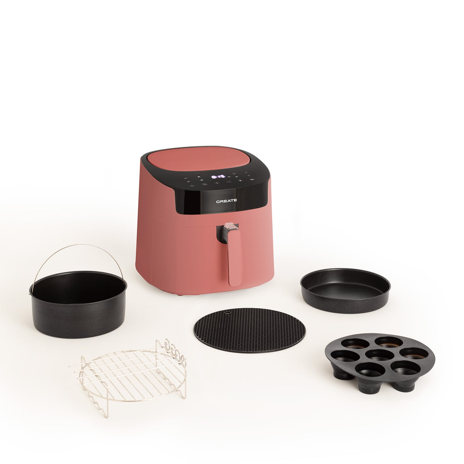 Una freidora de aire rosa con accesorios: cesta, rejilla, sartén redonda, rejilla y molde para magdalenas.