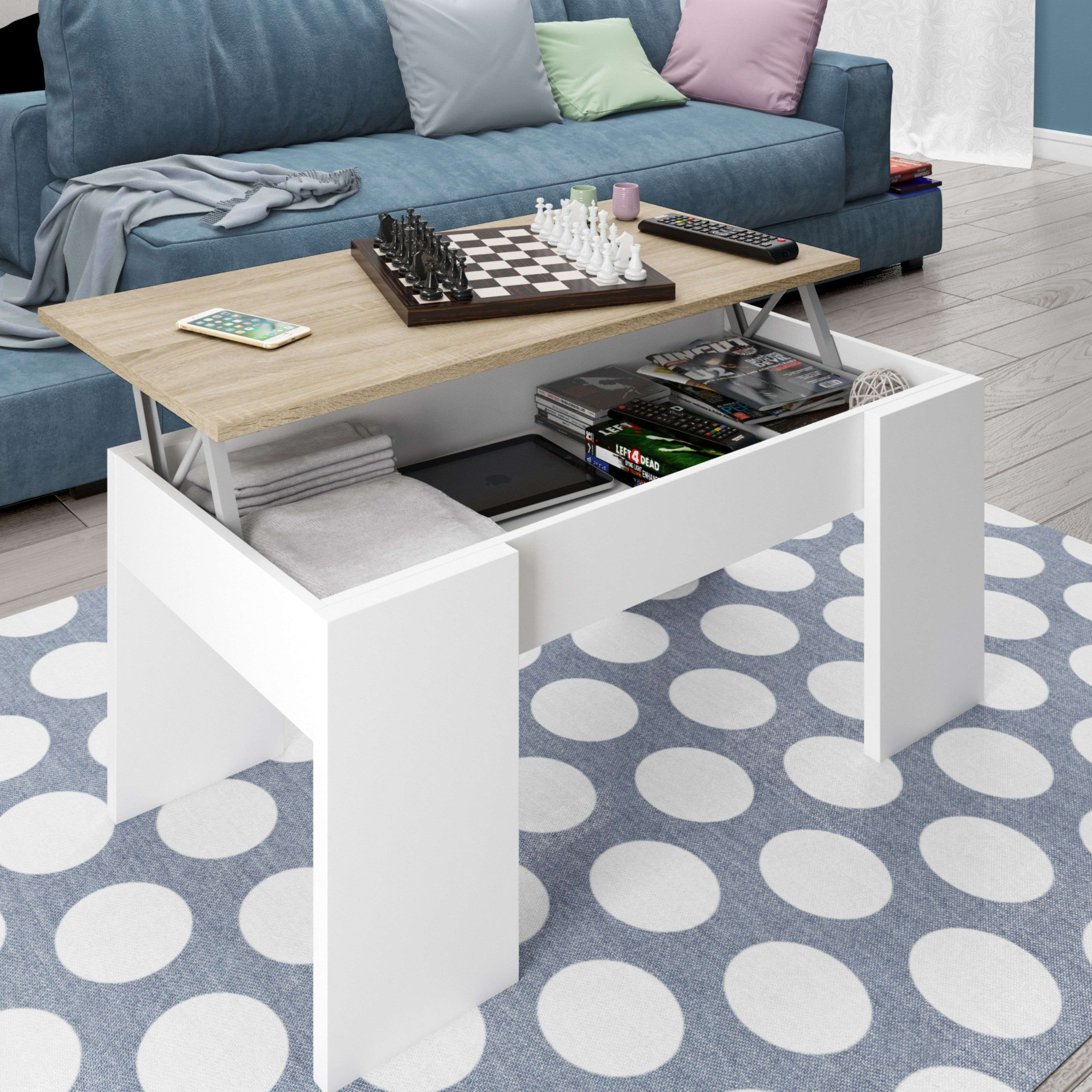 Una mesa de centro blanca con tapa elevable, ajedrez, mando y libros.