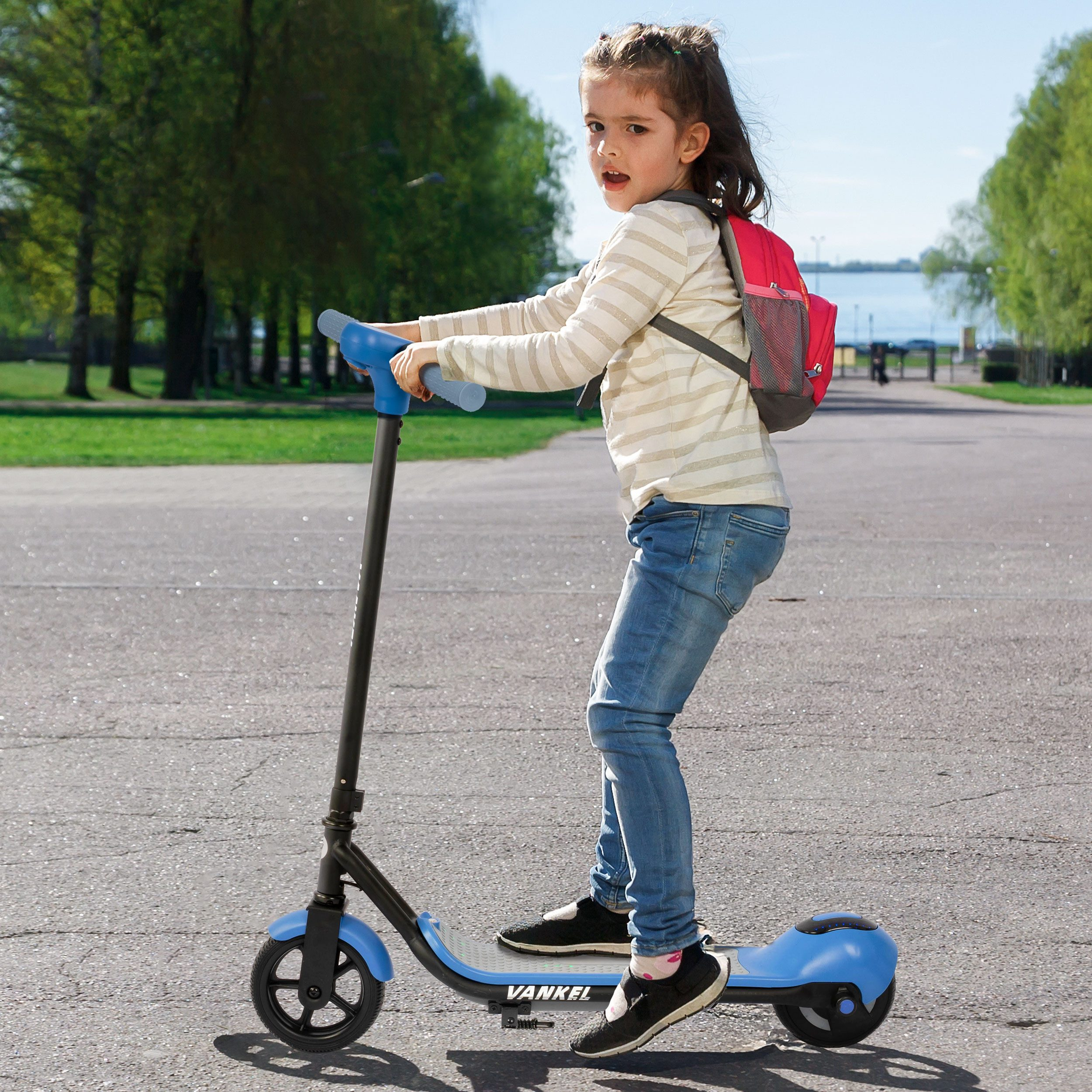Ein Mädchen fährt einen blauen Roller auf einem Gehweg, trägt einen roten Rucksack.