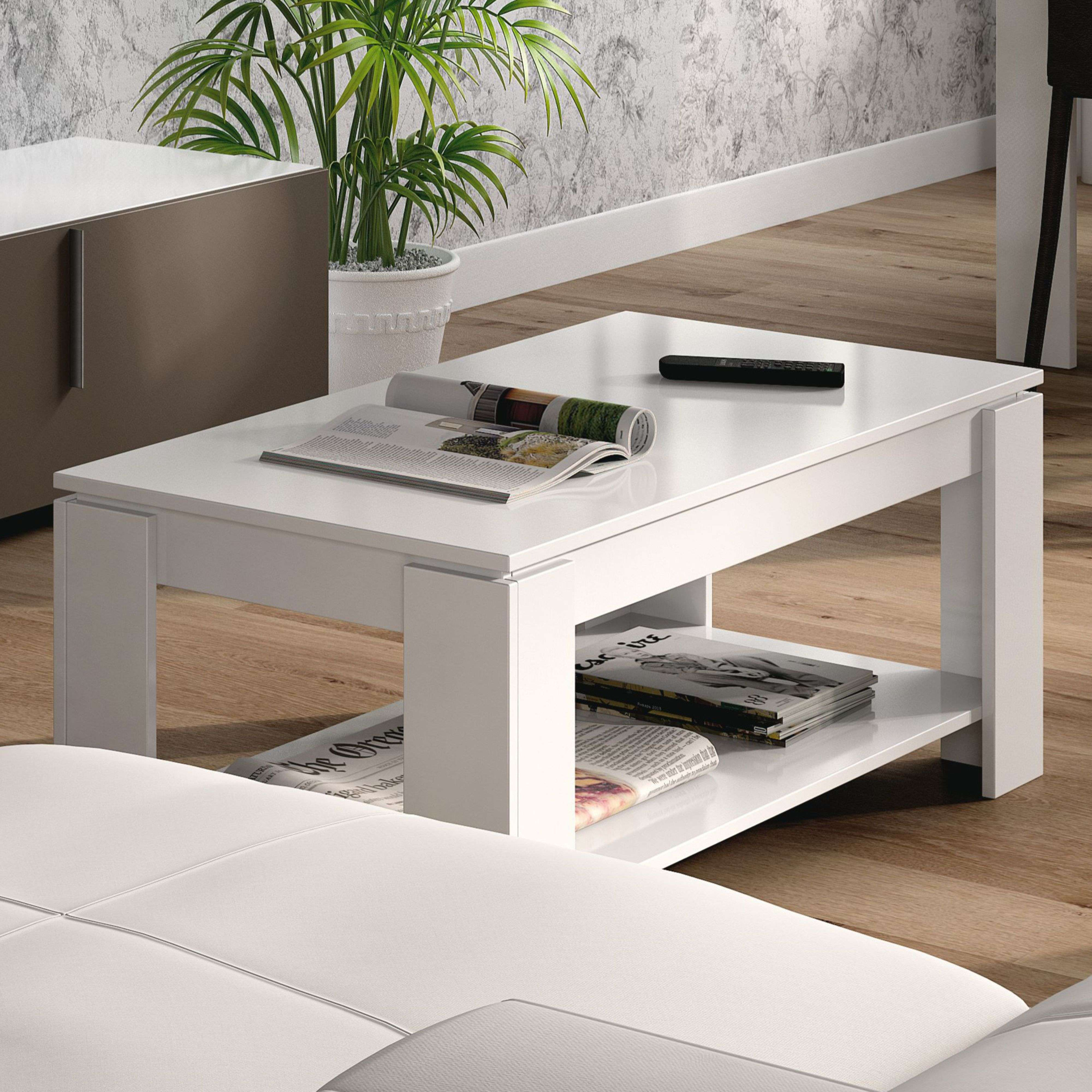 Una mesa de centro blanca con revistas y un control remoto encima.