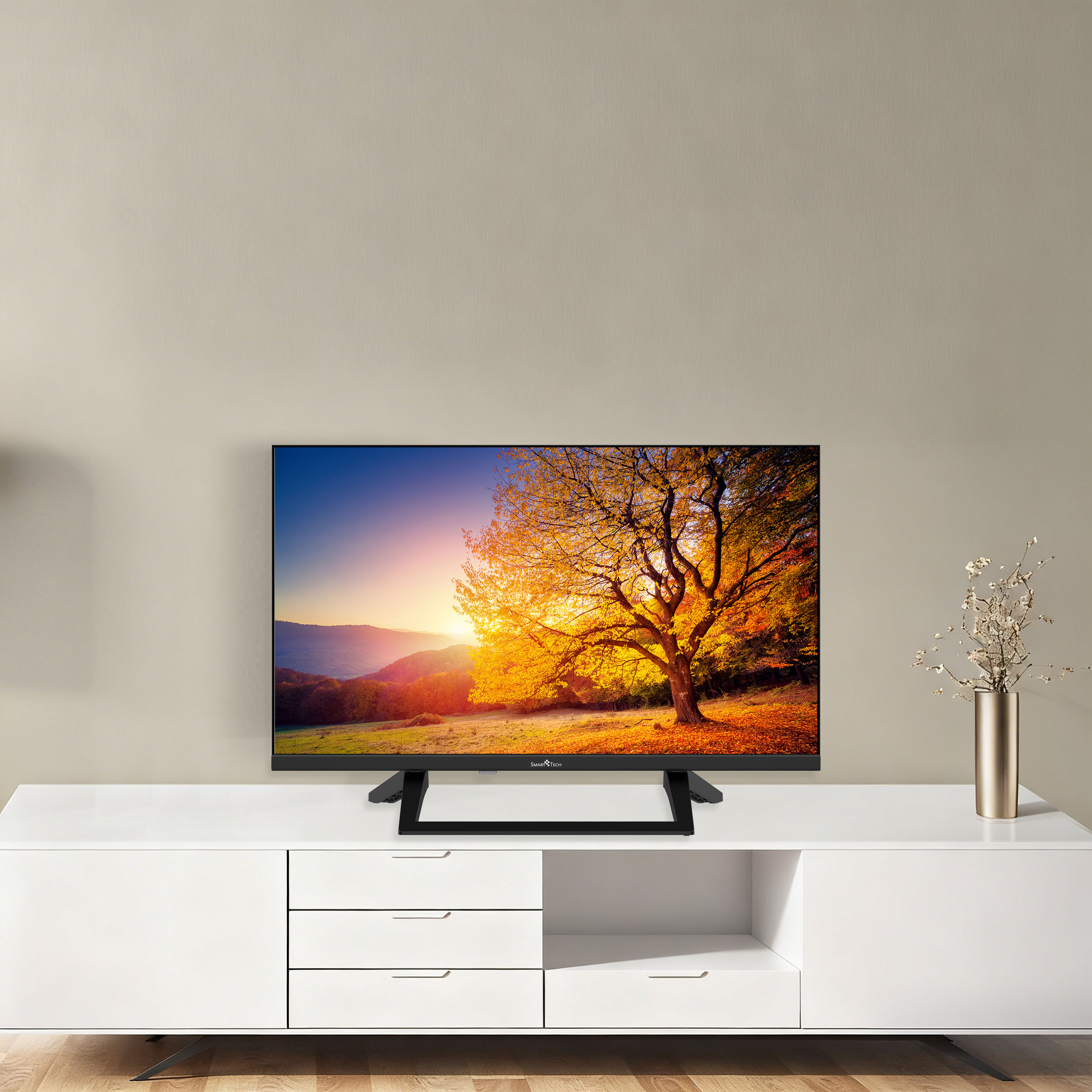 Un televisor moderno sobre un aparador blanco muestra un paisaje otoñal con un árbol.
