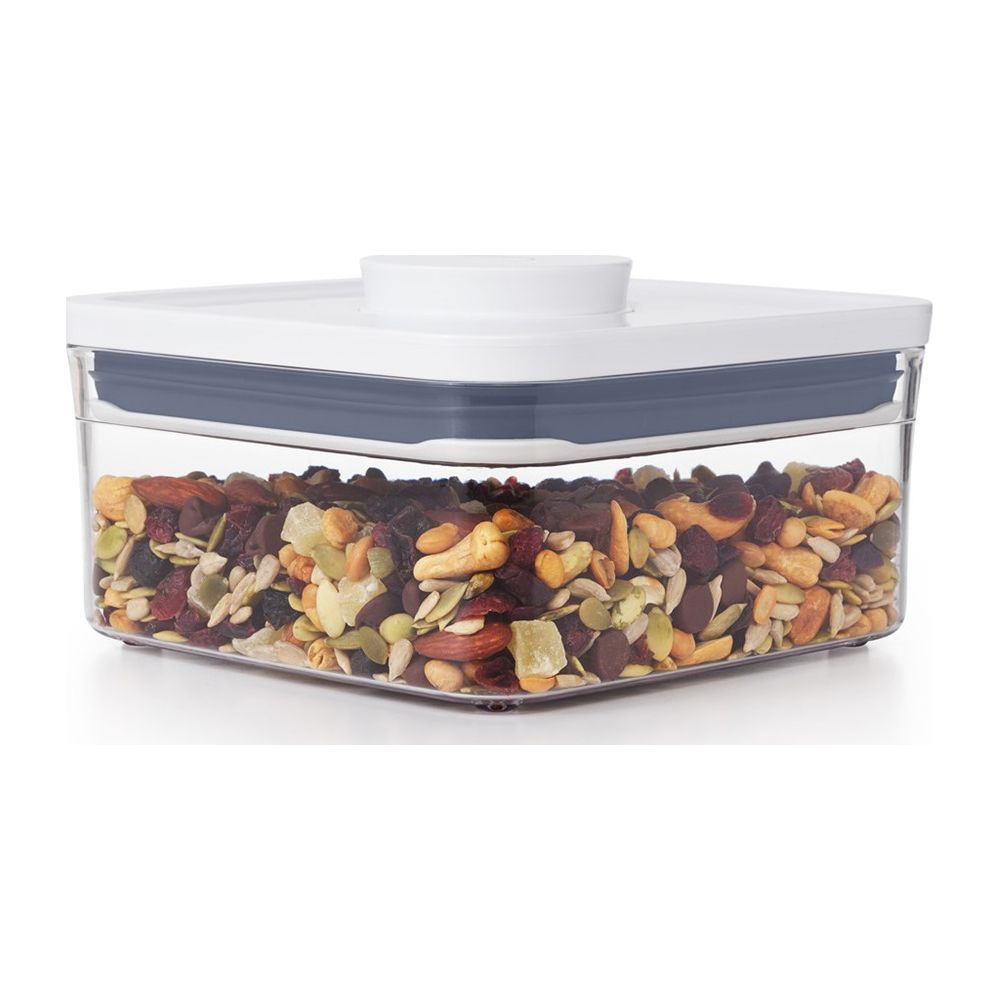 Un contenitore trasparente con coperchio bianco, riempito con un mix di frutta secca e noci.