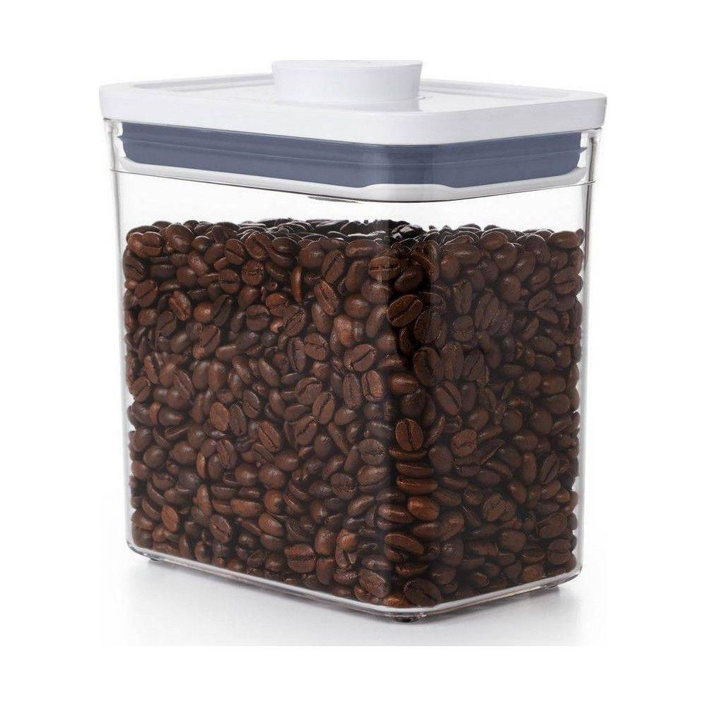 Un contenitore rettangolare trasparente pieno di chicchi di caffè tostati, con coperchio bianco.