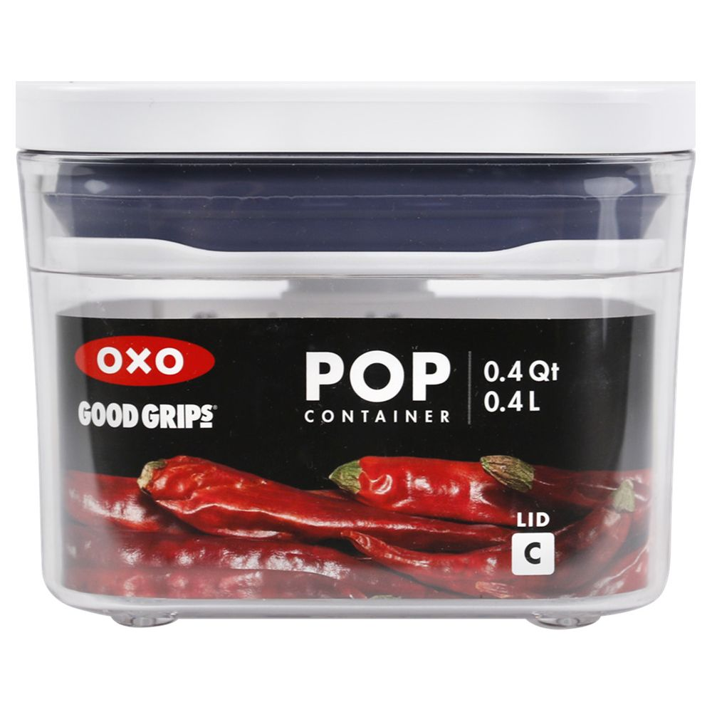 Un contenitore OXO Pop trasparente con coperchio bianco, riempito con peperoncini rossi.