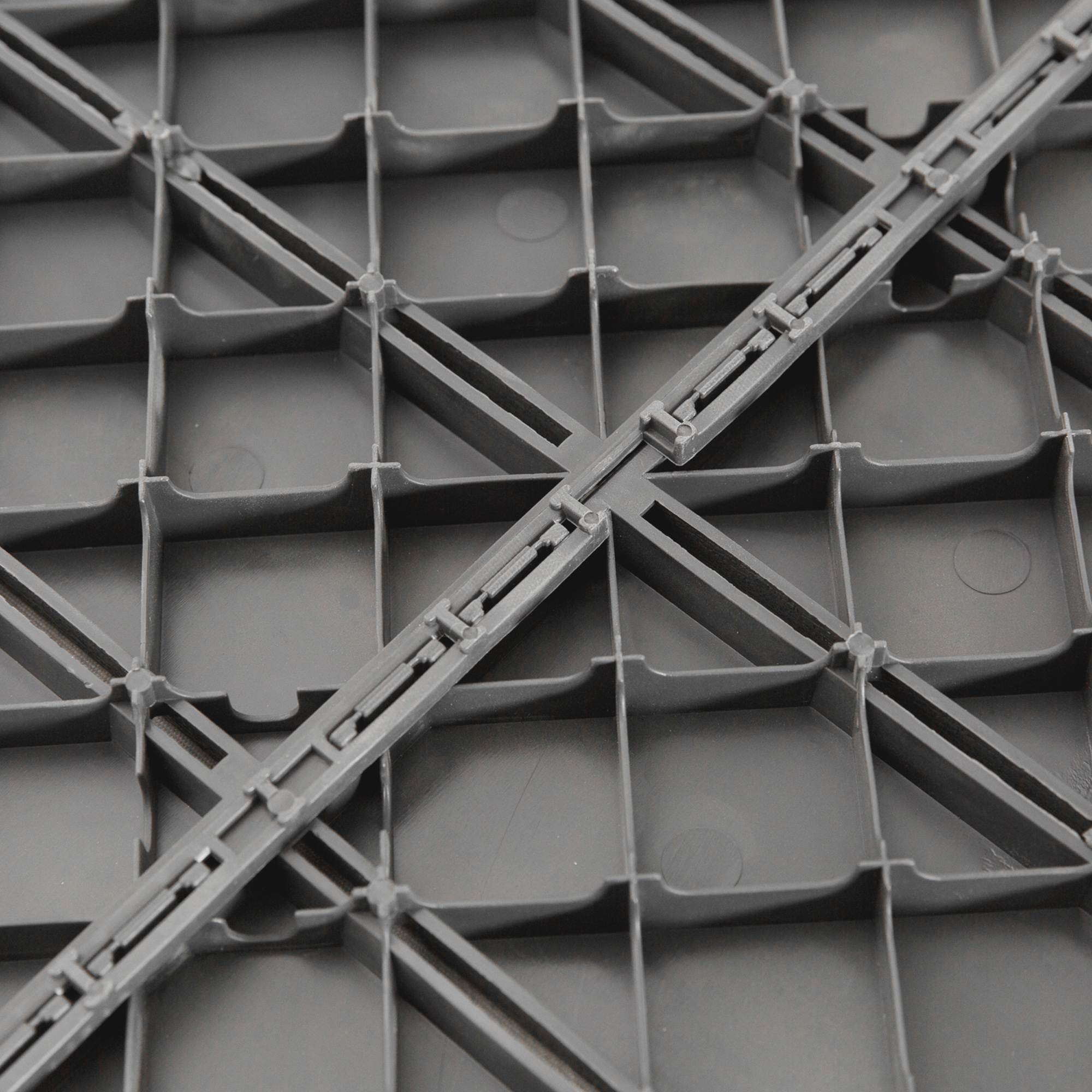 Primer plano de una estructura de rejilla de plástico gris con conexiones entrelazadas.