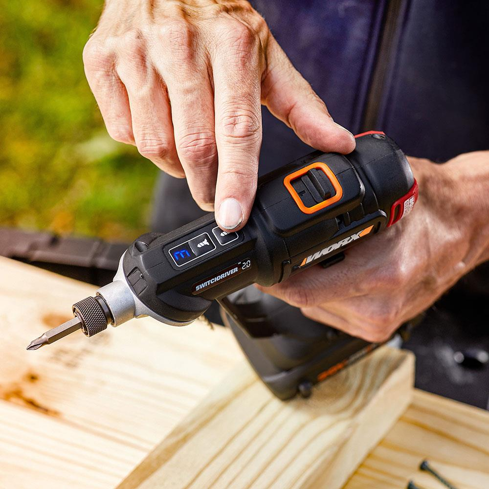 Mani az un trapano nero WORX Switchdriver 2.0 su assi di legno con viti.