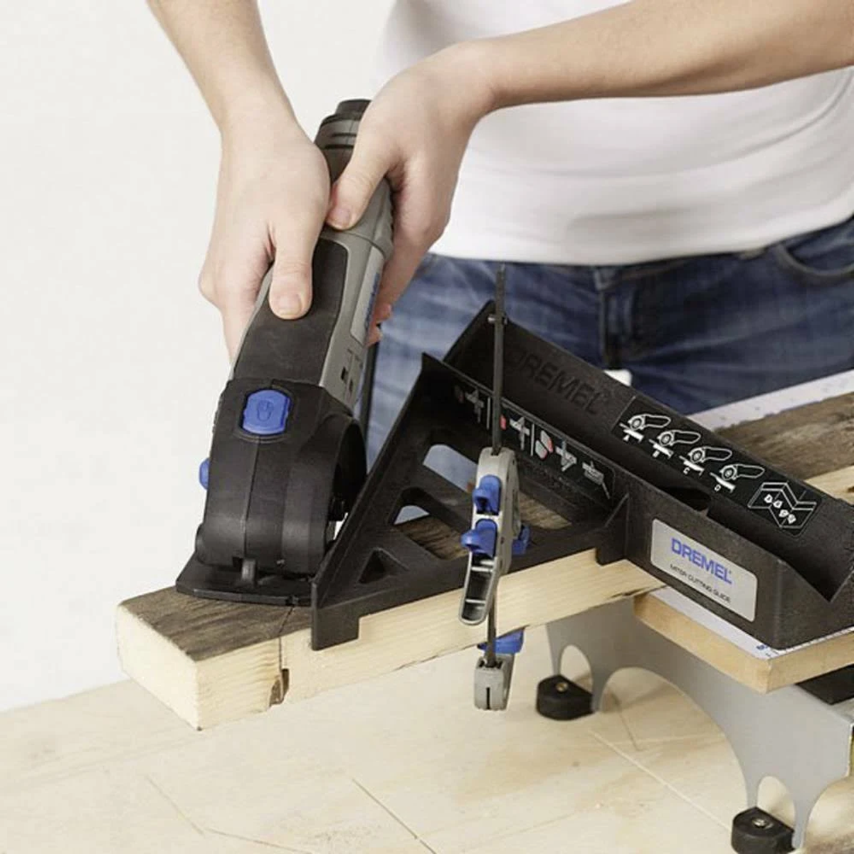 Una persona corta madera con una herramienta Dremel usando una guía de corte a inglete.