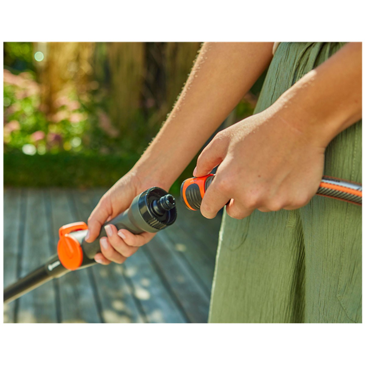Persona che collega tubo da giardino con due mani, primo piano.
