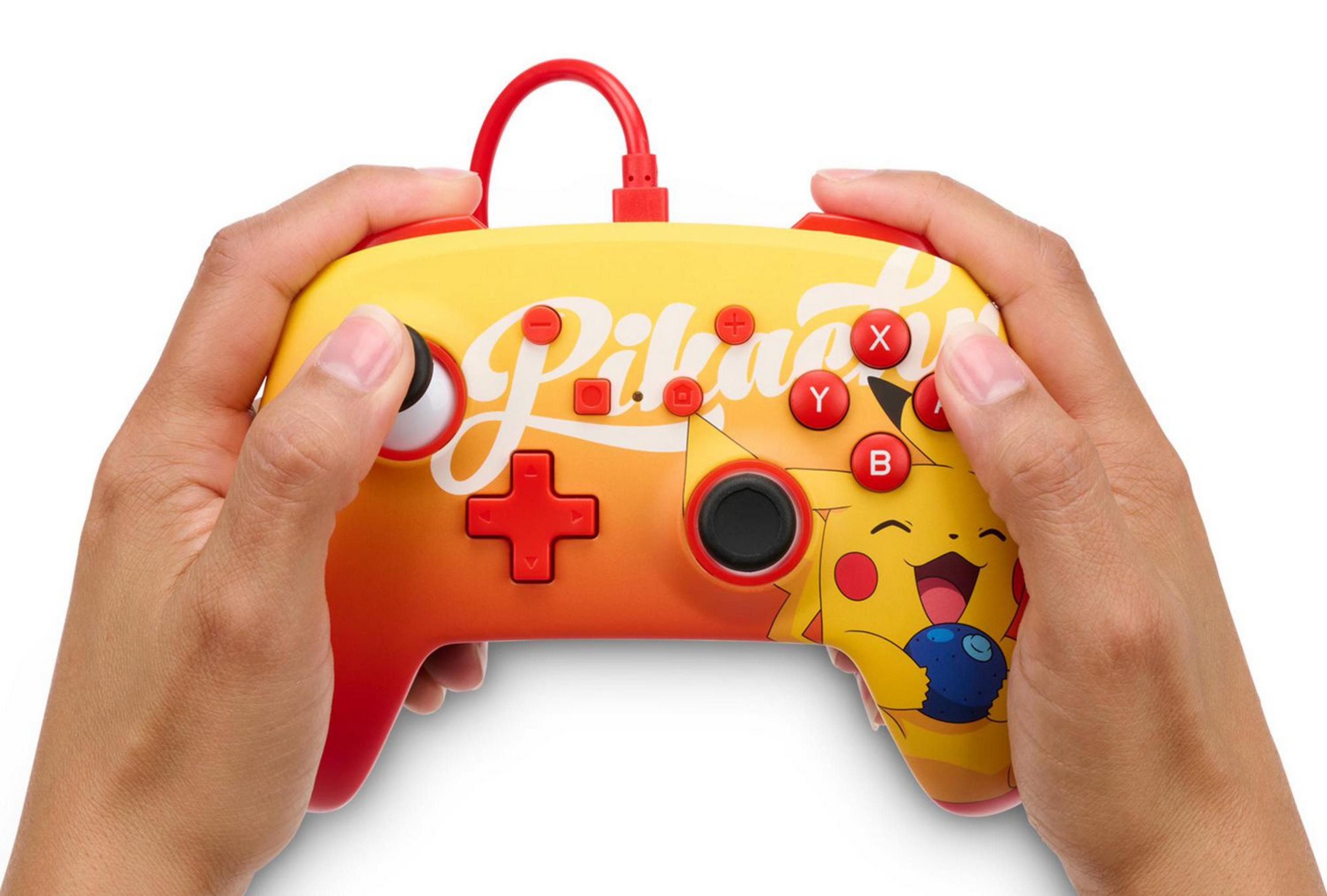 Hände halten einen gelben Controller mit Pikachu-Motiv und roten Knöpfen.