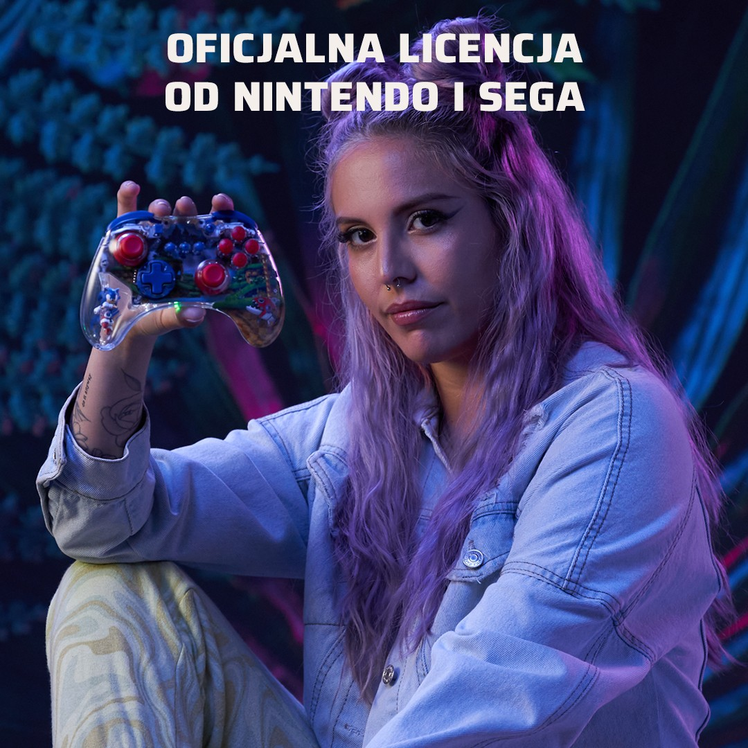 Eine Frau mit lila Haaren hält einen durchsichtigen Controller mit Sonic-Motiv.