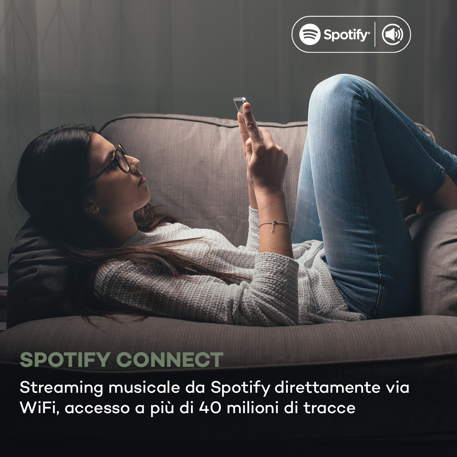 Frau liegt auf Sofa und benutzt ihr Smartphone, Spotify Logo oben.