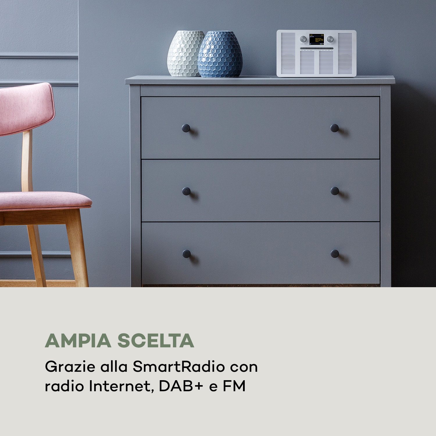 Grauer Schrank mit zwei Vasen und einem weißen Radio, daneben ein rosafarbener Stuhl.