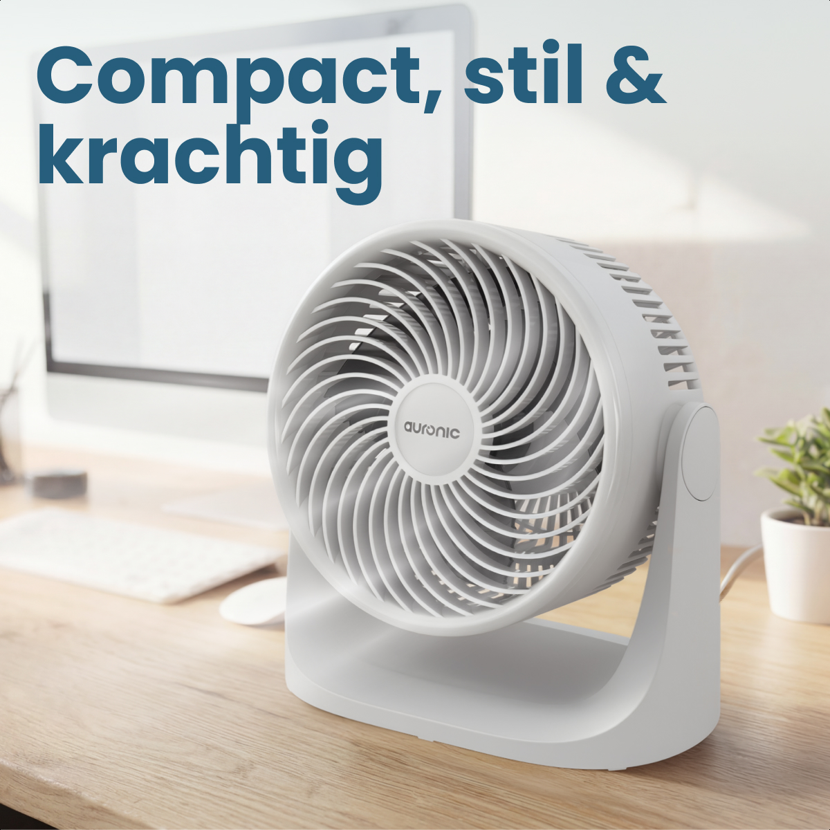 A white desk fan sits on a wooden desk. A computer is in the background.