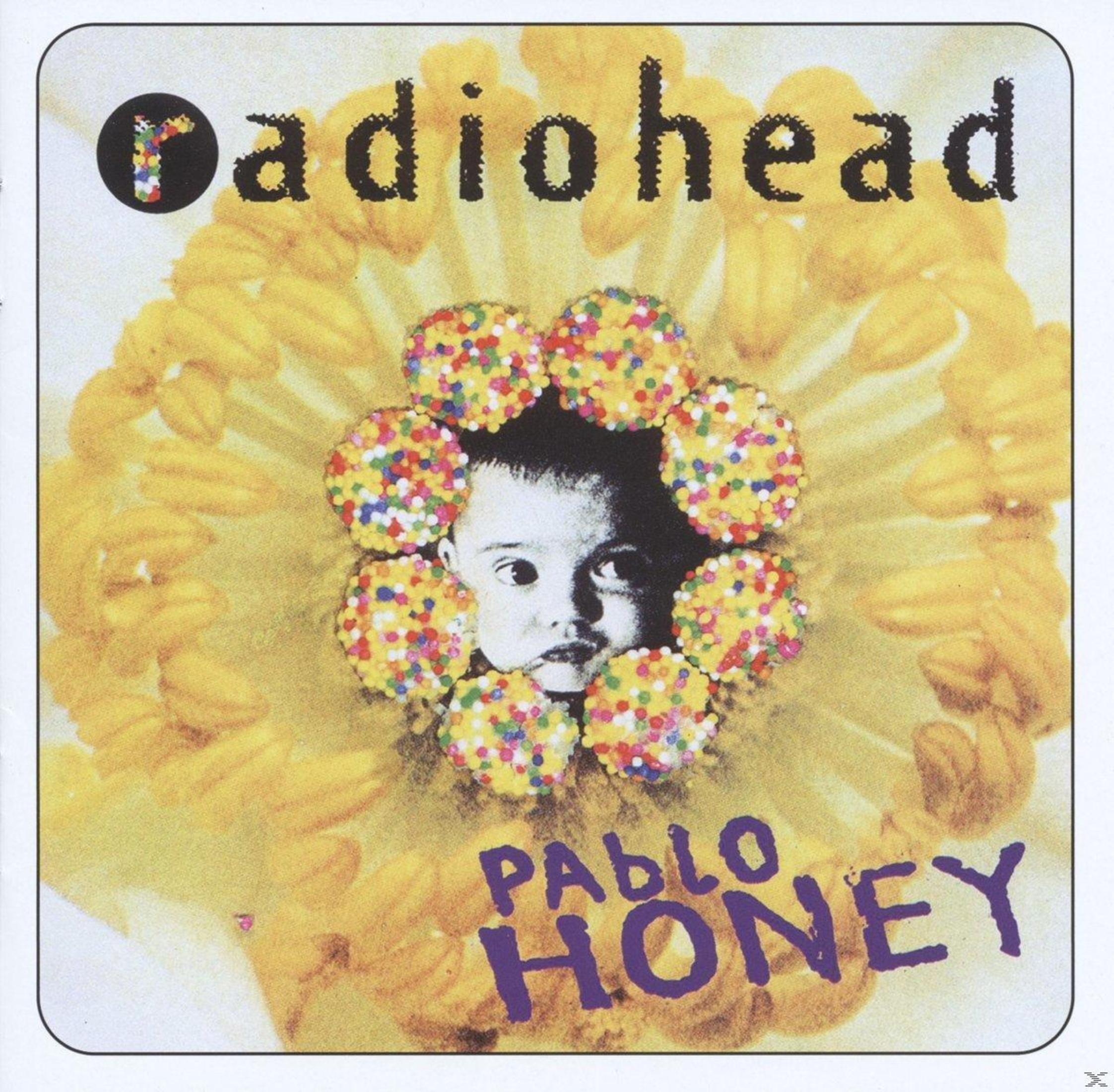 La cara de un bebé mira a través de una flor amarilla, rodeada de chispas coloridas. Texto "Radiohead Pablo Honey".