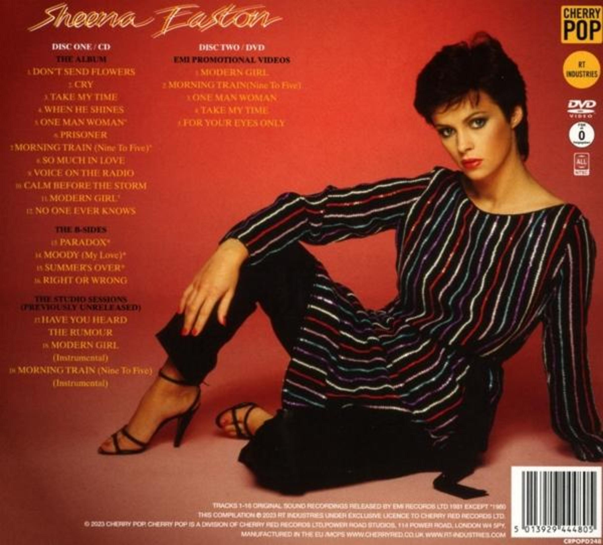 Sheena Easton zit op een rode achtergrond, met een gestreept topje en zwarte broek.