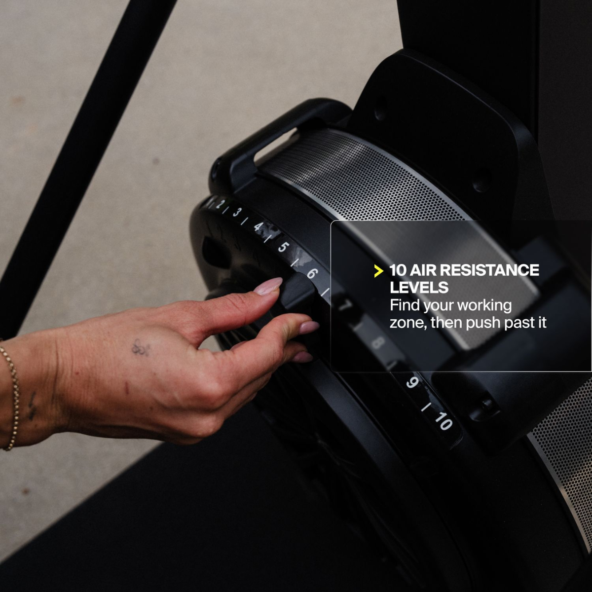 A hand adjusts a black dial with numbers 1-10 for air resistance.